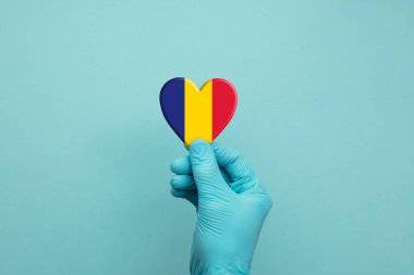 Romanya bayrağı taşıyan koruyucu ameliyat eldivenleri takan eller