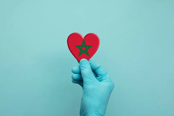 Manos con guantes quirúrgicos protectores que sostienen el corazón de Marruecos — Foto de Stock