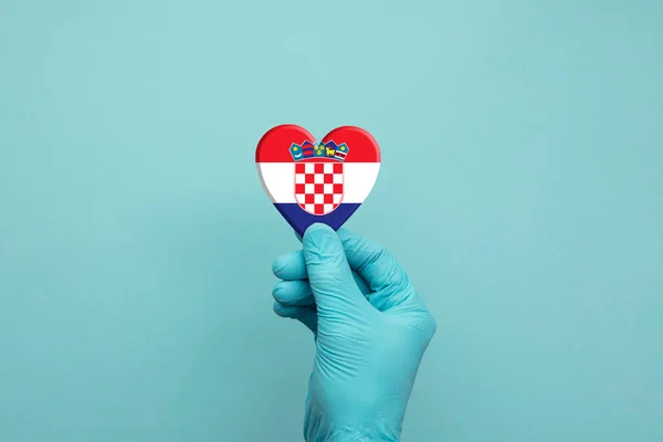 Χέρια με προστατευτικά χειρουργικά γάντια που κρατούν την καρδιά της Κροατίας — Φωτογραφία Αρχείου
