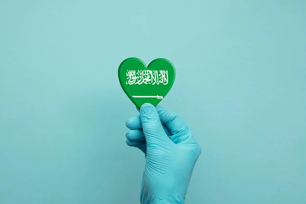 Manos con guantes quirúrgicos protectores que sostienen el corazón de Arabia Saudita —  Fotos de Stock