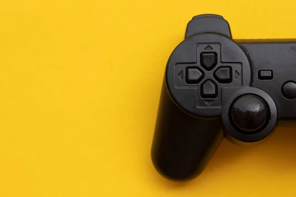 亮黄色背景的黑色视频游戏控制器 — 图库照片