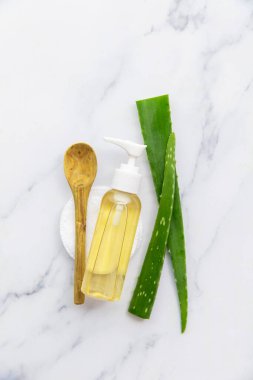 Aloe vera kozmetik şişesi ve doğal yeşil aloe vera yaprakları.
