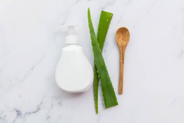 Aloe vera doğal cilt bakımı. Yeşil yapraklı beyaz ürün şişesi. Düz konum