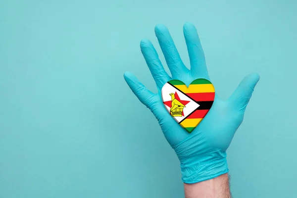 Zimbabwe medical health heart. Nurse hand holding country heart flag