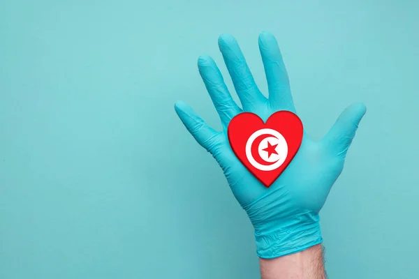 Tunisia medical health heart. Nurse hand holding country heart flag