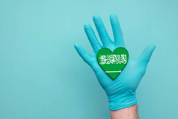 Saudi Arabia medical health heart. Nurse hand holding country heart flag