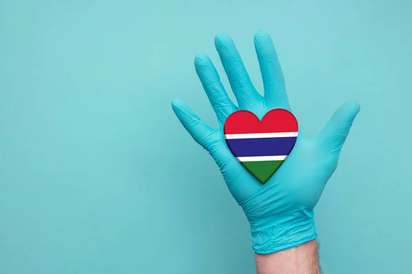 Gambia medical health heart. Nurse hand holding country heart flag