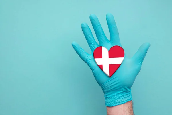 Dinamarca salud médica corazón. Enfermera mano sosteniendo bandera del corazón del país —  Fotos de Stock