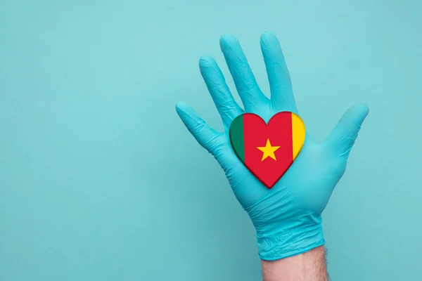 Ιατρική καρδιά Καμερούν. Σημαία καρδιάς χώρας με το χέρι νοσοκόμας — Φωτογραφία Αρχείου