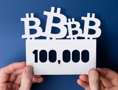 Ellerinde bir bitcoin kripto para var. 100,000 piyasa fiyatı işareti.