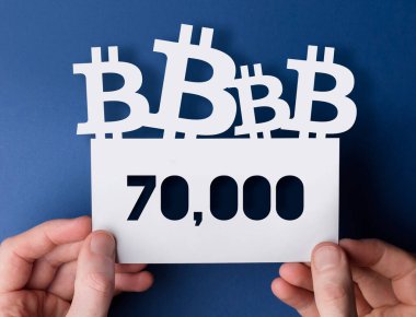 Ellerinde bir bitcoin kripto döviz 70.000 piyasa fiyatı işareti var.