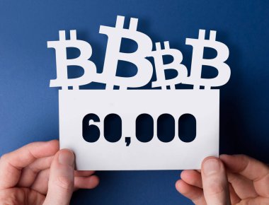 Ellerinde bir bitcoin kripto para birimi var. 60,000 piyasa fiyatı işareti.