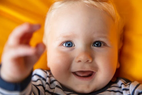 Gros plan d'un mignon bébé garçon de 9 mois aux yeux bleus sur fond jaune — Photo