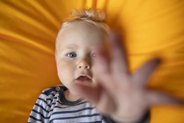 Gros plan d'un mignon bébé garçon de 9 mois aux yeux bleus sur fond jaune — Photo