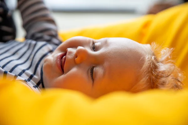 Primo piano di un simpatico bambino di 9 mesi con gli occhi azzurri su uno sfondo giallo — Foto Stock