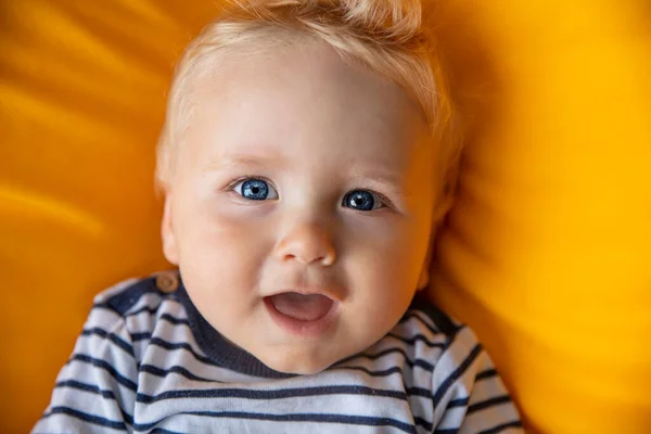 Gros plan d'un mignon bébé garçon de 9 mois aux yeux bleus sur fond jaune — Photo