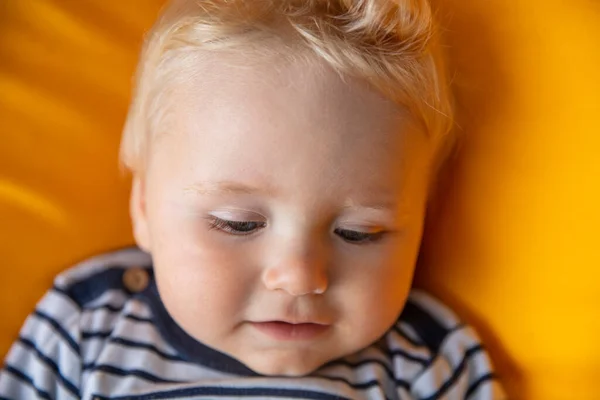 Close up de um menino bonito de 9 meses de idade com olhos azuis em um fundo amarelo — Fotografia de Stock