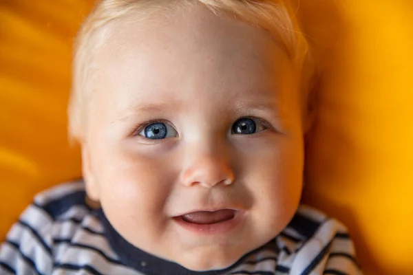 Close up of a cute 9 month old baby boy with blue eyes on a yellow background — Stock Photo, Image