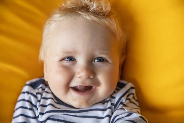 Gros plan d'un mignon bébé garçon de 9 mois aux yeux bleus sur fond jaune — Photo