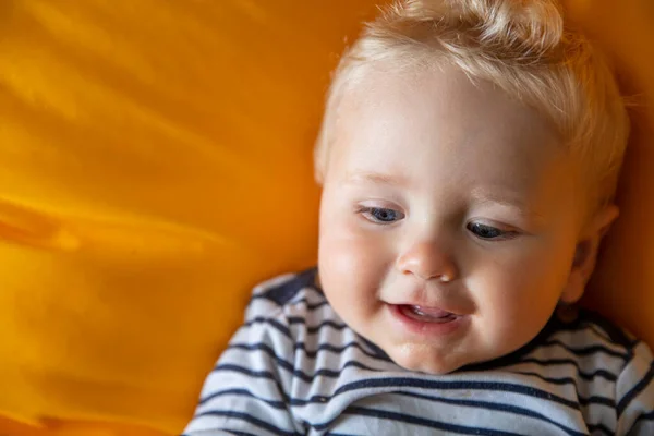Close up de um menino bonito de 9 meses de idade com olhos azuis em um fundo amarelo — Fotografia de Stock