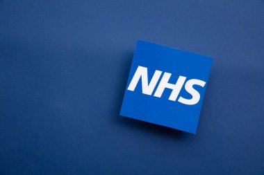 LONDON, İngiltere - Temmuz 2021: Mavi arka planda NHS Ulusal Sağlık Hizmetleri logosu