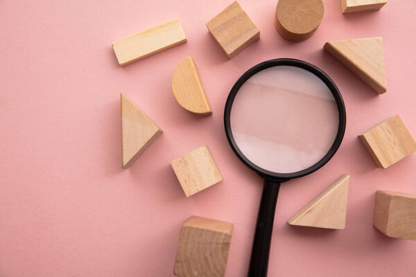 Magnifying glass with a selection of different shaped wooden blocks