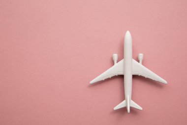 Pastel pembe arka planda beyaz oyuncak uçak. Kopya alanı ile uçuş seyahat arkaplanı