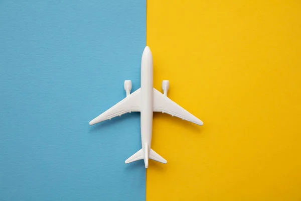 Plano de una aeronave de pasajeros blanca sobre un fondo azul brillante y amarillo —  Fotos de Stock