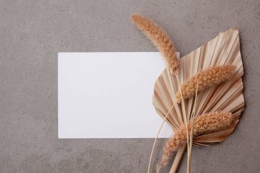 Doğal kurutulmuş palmiye yaprağı ve otlarla çevrili bohem boş davetiye kartı. Düğün ve kutlama geçmişi