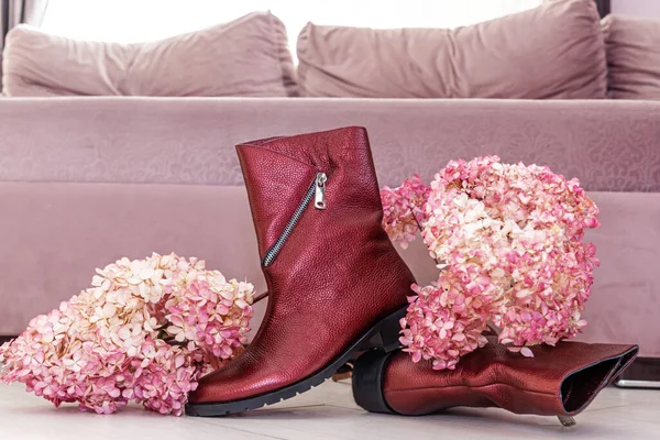 Stylish boots with low heels and fresh lilac flowers in room