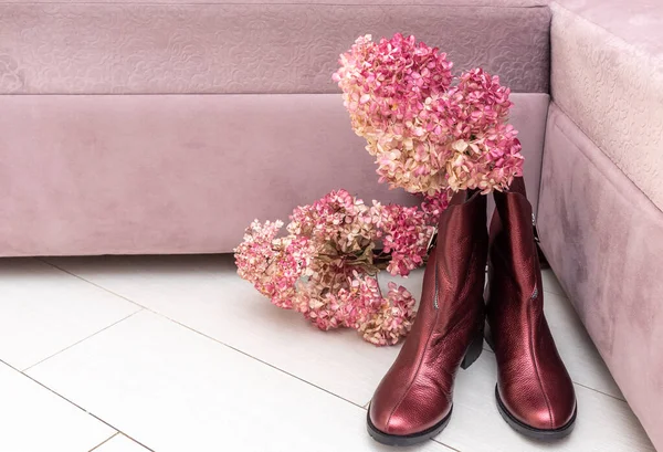 Red boots with low heels and lilac on floor near pink sofa