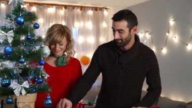 Bir çift oturma odasında Noel ağacı süslemekten zevk alıyor. Tatil hazırlığı.