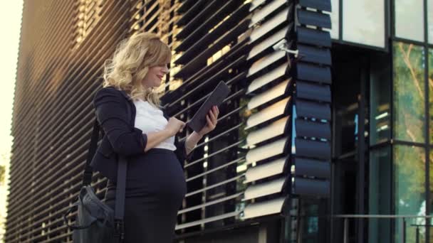 一位面带微笑的女商人站在一座现代建筑前 一边读着平板电脑上的一些东西 — 图库视频影像
