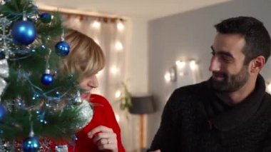 Bir çift oturma odasında Noel ağacı süslemekten zevk alıyor. Tatil hazırlığı.