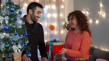 Oturma odasındaki Noel ağacında eğlenen ve hediyelerini paylaşan bir çift. Tatil hazırlığı.