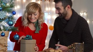 Oturma odasındaki Noel ağacında eğlenen ve hediyelerini paylaşan bir çift. Tatil hazırlığı.