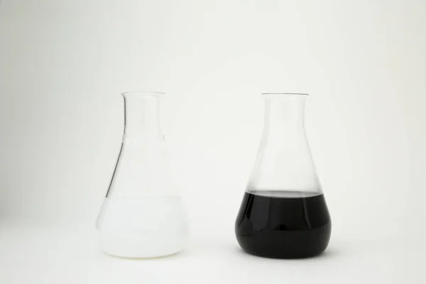 科学实验室的玻璃瓶 装有白色和黑色液体 背景为白色 — 图库照片