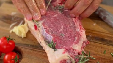 Aşçının ellerinin, tereyağını sürdüğü ve bir parça ete başka baharatlar kattığı hazırlık aşamasında yakın plan çekimi..