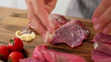 Aşçının ellerinin, tereyağını sürdüğü ve bir parça ete başka baharatlar kattığı hazırlık aşamasında yakın plan çekimi..