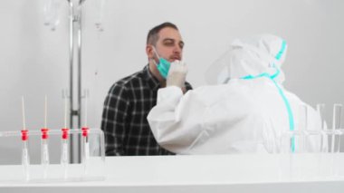 COVID-19 testi yapan bir tıp çalışanı hastane laboratuvarındaki erkek hastadan burun temizleme örneği Coronavirus için PCR testi, test kiti kullanan bir doktor..