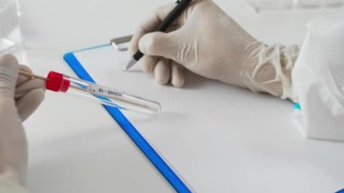 PPE 'de hastane laboratuvarında COVID-19 testi yapan bir tıp çalışanı. Sonuçları yazıyor..
