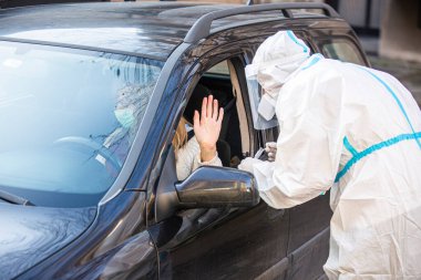 Kadın sürüş sırasında COVID 19 testi yapmayı reddediyor. Hastanın burnundan araba camından DNA örneği alıyor. PCR teşhisi koyuyor. Pasaportları var..