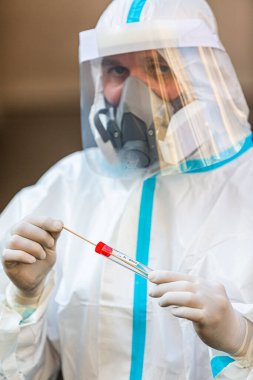 COVID-19 testi yapan bir tıp çalışanı, hastadan alınan burun temizleme örneği için. Koronavirüs için PCR teşhisi, PPE 'deki doktor test kiti tutuyor..