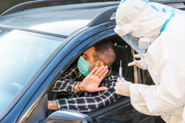 Adam sürüş sırasında COVID 19 testi yapmayı reddediyor. Hastanın burnundan araba camından DNA örneği alıyor. PCR teşhisi koyuyor. Pasaportları var..