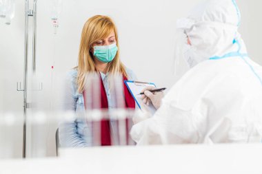 COVID-19 hastanesindeki hastayı muayene eden sağlık çalışanı. Coronavirus için PCR teşhisi. PPE 'deki doktor hastalara semptomlar yazıyor..