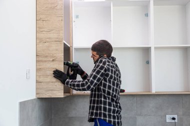 Bir marangoz hem matkapla çalışır hem de aynı zamanda cep telefonuyla biriyle konuşur..