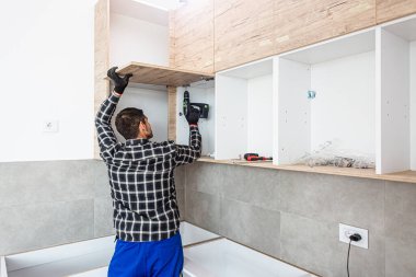 Marangoz mutfak raf kapısının mekanizmalarını (eklemlerini) kurar ve vidalar.