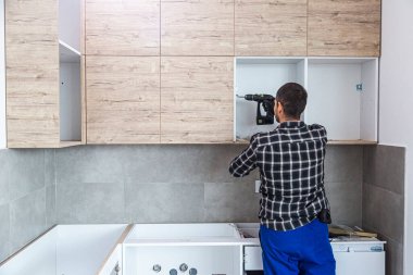 Marangoz duvardaki mutfak rafının montajını tamamlıyor..