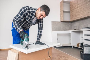 Bir marangoz, mutfak asma elementinin rafları için tasarlanmış ahşap yüzeyin bir parçasını kesiyor..