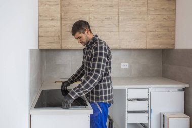 Marangoz, indüksiyon hobını mutfağın neredeyse bitmiş mutfağına yerleştirir..